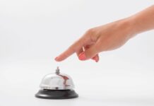Hand van een vrouw die een hotelbel bedient; dit beeld is een metafoor voor het claimende gedrag door mantelzorgers richting zorgverleners.