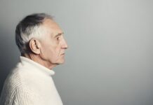 Sad senior man isolated on gray background. Studio portrait. Dementia and Alzheimer's disease concept. Memory loss awareness. Banner with copy space *** Local Caption ***